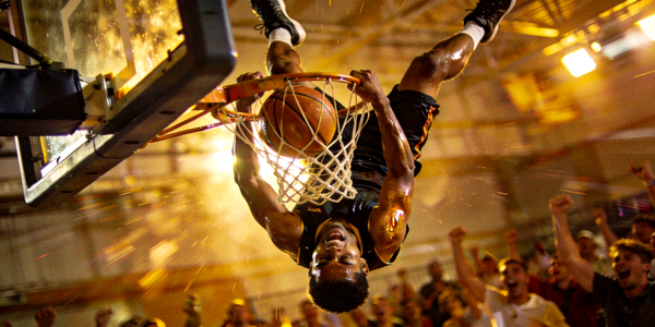 篮球比赛中球员完成霸气扣篮后悬挂在篮筐上的瞬间